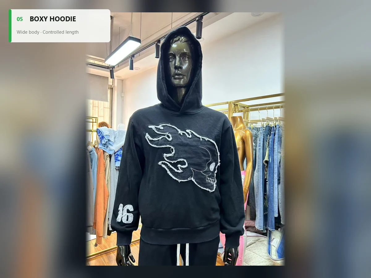 Black boxy hoodie with a wide straight body and skull appliqué on a mannequin