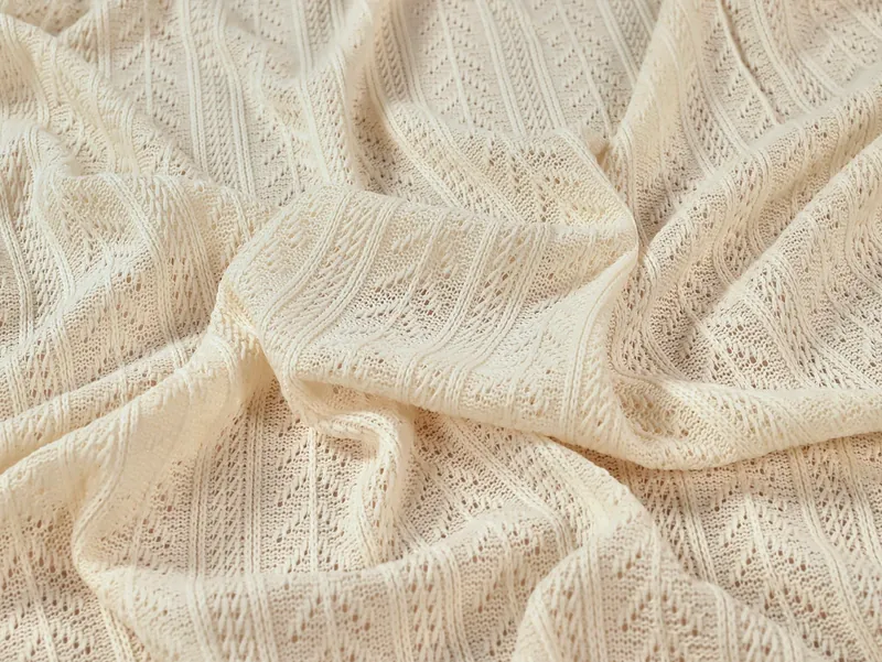 Cream openwork fabric with delicate patterned texture and flowing folds