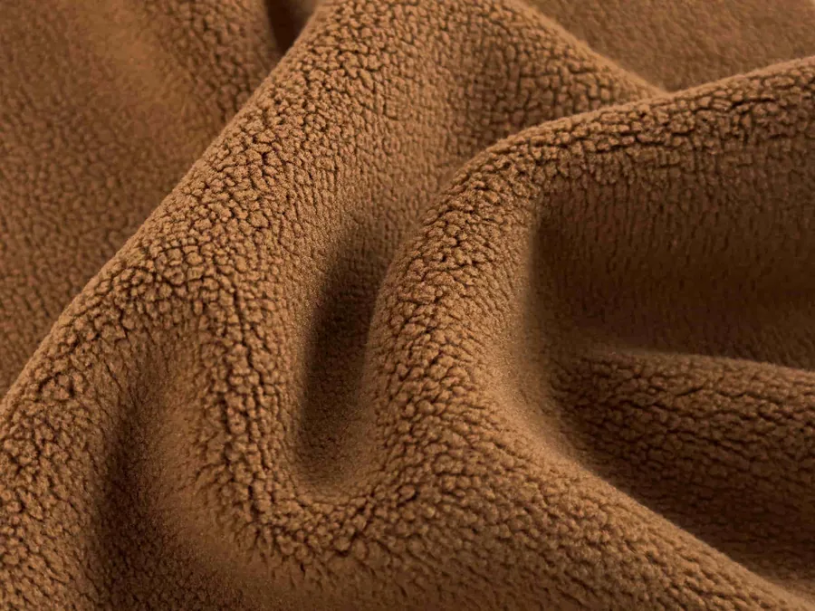 Camel brown fleece fabric with a textured pile surface and deep folds