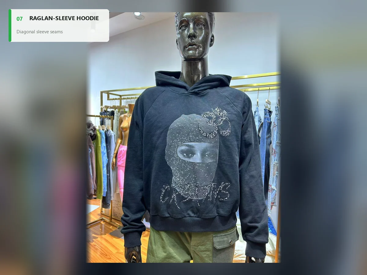 Black raglan-sleeve hoodie with diagonal shoulder seams and a rhinestone face graphic
