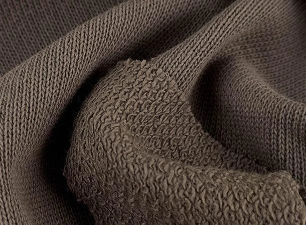 Brown terry fabric showing its looped reverse and smooth knit face